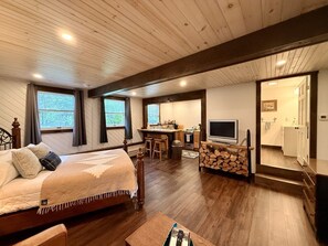 Une chambre avec un lit, une télévision, un coin cuisine comprenant une table à manger et une cheminée.