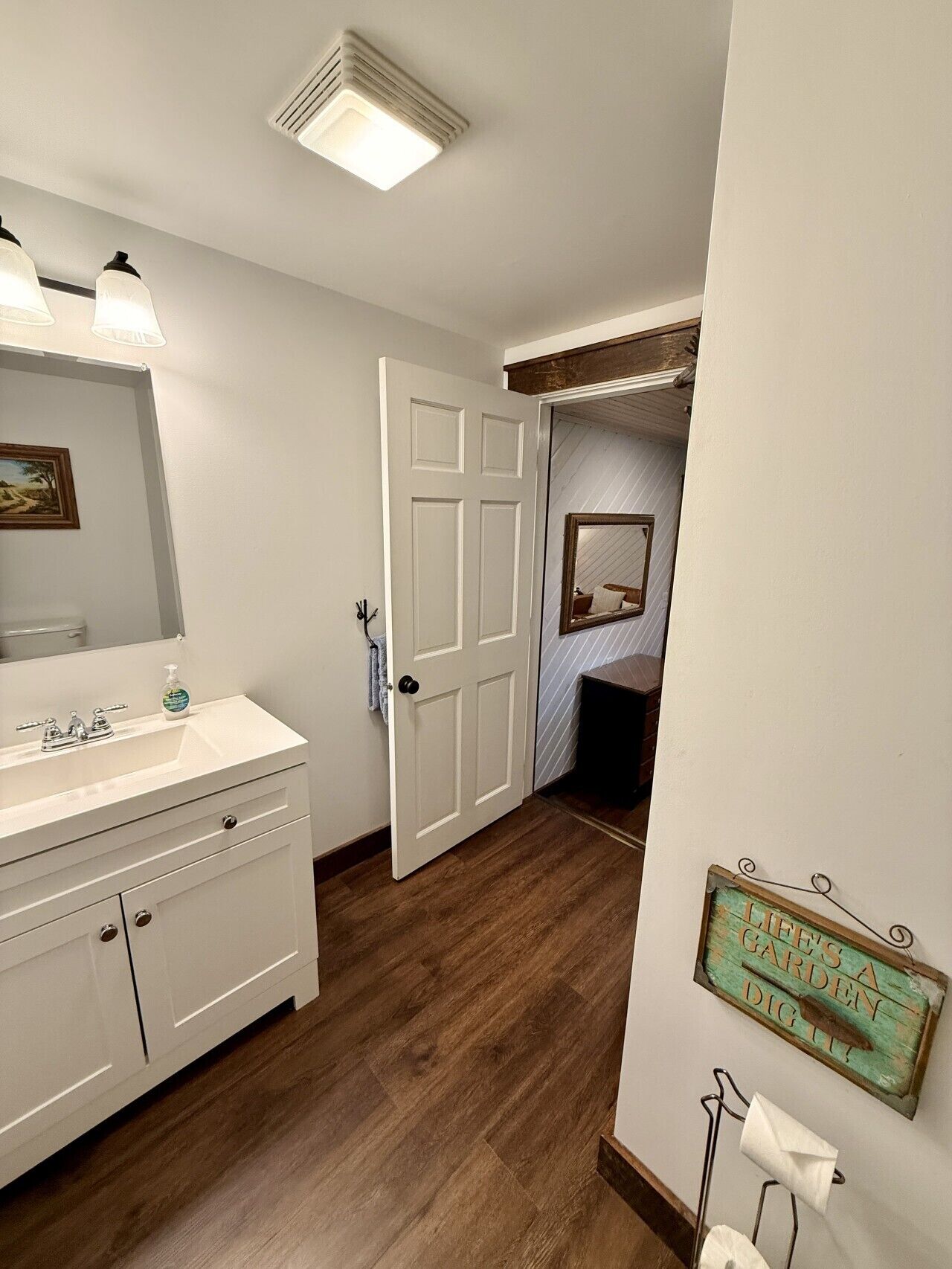Une salle de bain avec un meuble-lavabo blanc, un miroir, des toilettes et un espace douche.