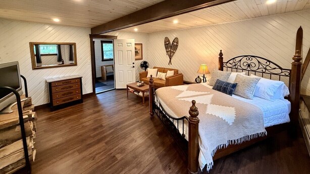 A bedroom with a wooden bed, a dresser, a desk, and a chair.