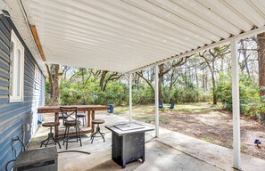A covered patio with a table and chairs, a grill, and a view of a wooded area. - 4 Mi to UF: Pet-Friendly Home w/ Yard & Deck (Gainesville)