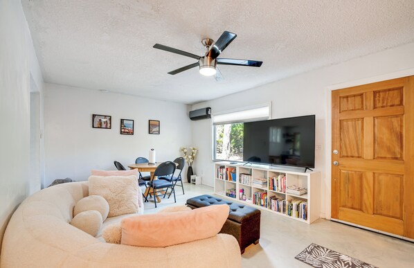 A living room with a ceiling fan, a TV, a bookshelf, and a wooden door. - 4 Mi to UF: Pet-Friendly Home w/ Yard & Deck (Gainesville)