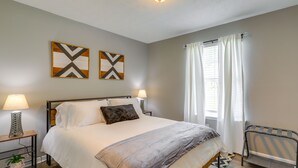 Un dormitorio ordenado con cama, lámparas de noche, mesitas de noche y una ventana con cortinas.