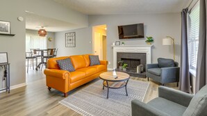 Una sala de estar moderna con sofá, sillones, chimenea y televisor.