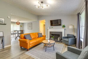 Una sala de estar con sofá, sillones, una mesita de centro, chimenea y televisión.