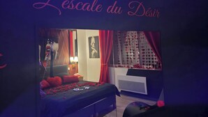 A bedroom with a bed, a nightstand, a dresser, a window with curtains, and a wall-mounted artwork. - L'escale du Desir Love Room spa Privatif (Calais)