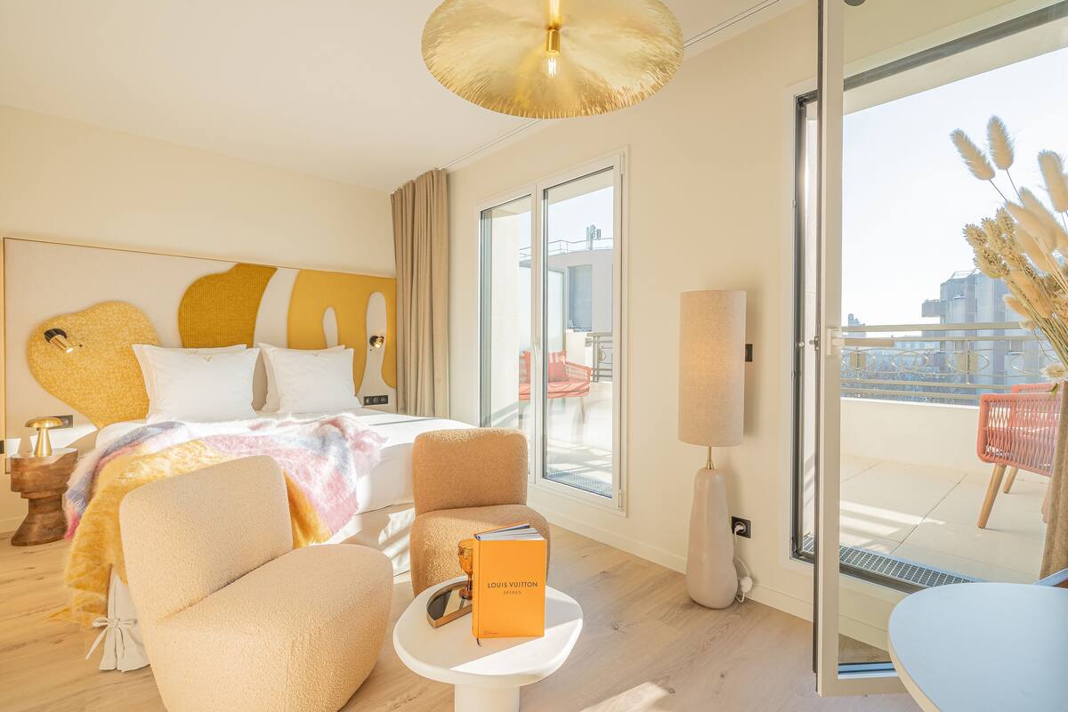 Ein Hotelzimmer mit einem Bett, einem Sessel, einem kleinen Tisch und Blick auf den Balkon.