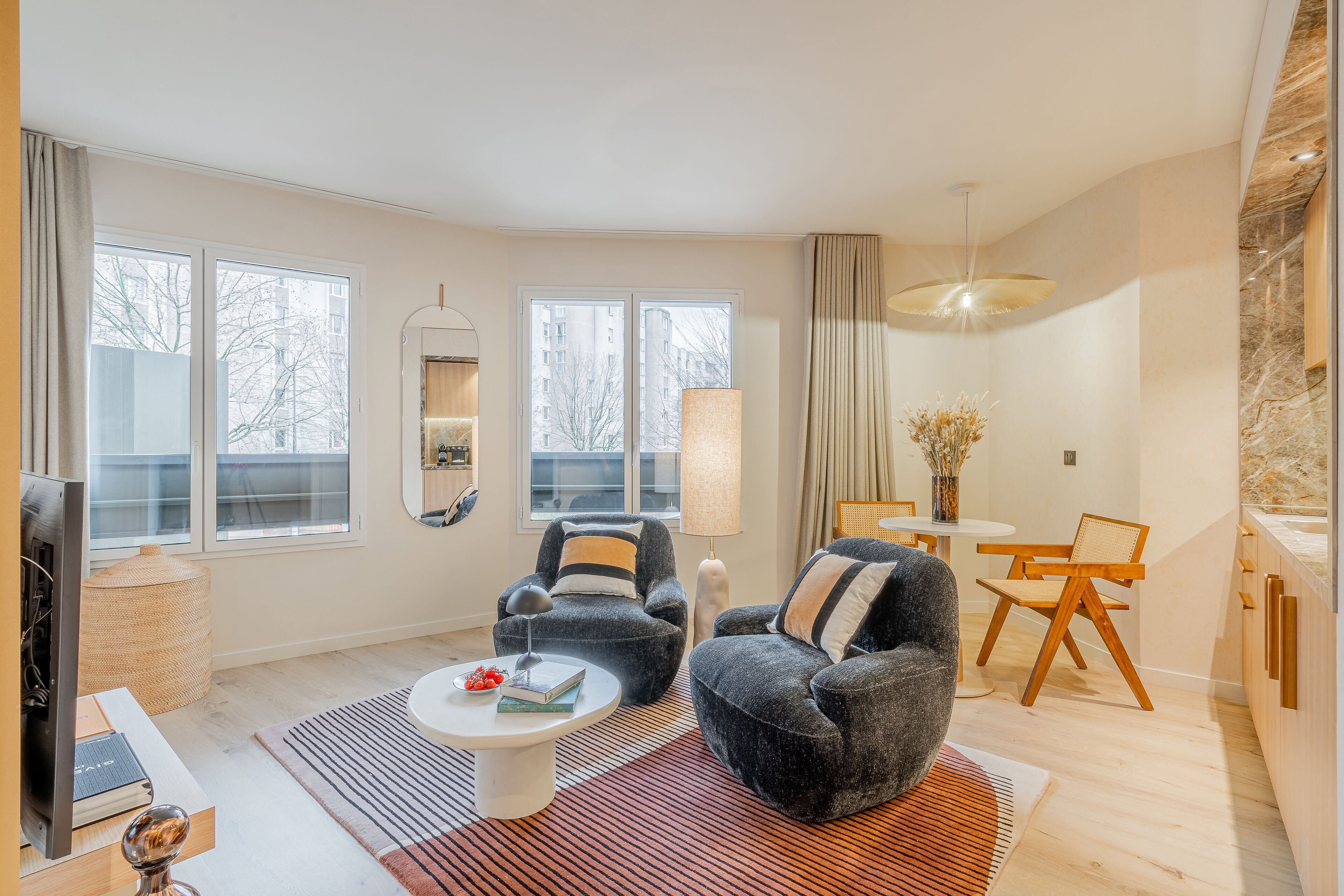 A modern living room with a sofa, armchair, coffee table, and dining area.