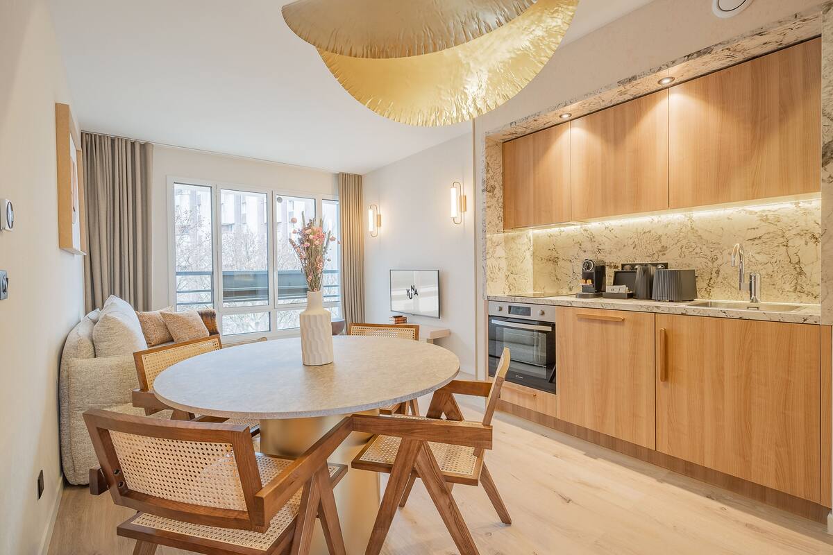 Eine moderne Küche mit Holzschränken, einer Marmorarbeitsplatte und einem eingebauten Backofen.