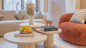 A modern living room with a beige sofa, a red sofa, a round coffee table, and a tall floor lamp. - Yuna Porte Maillot - ApartHotel (Paris)