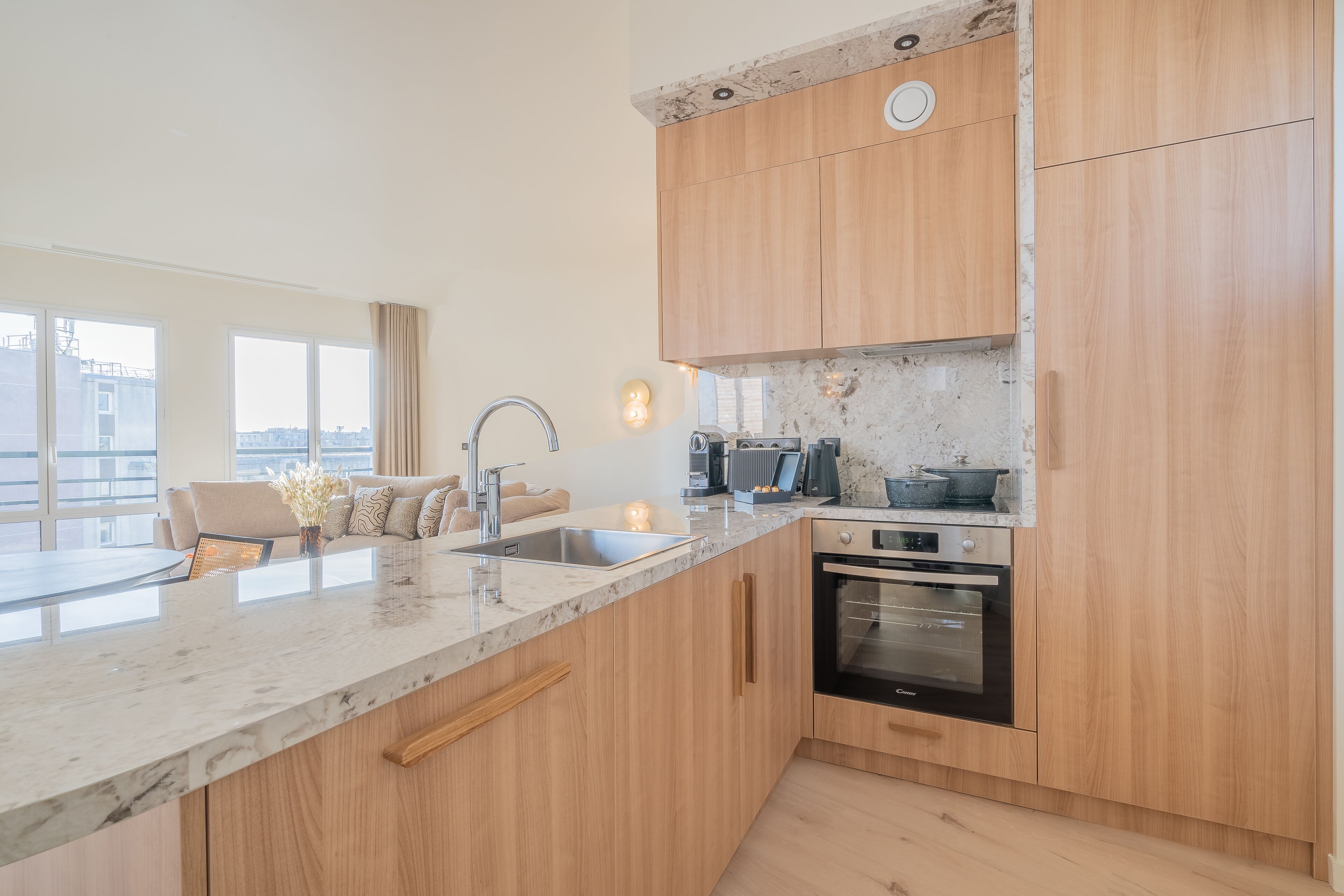 Eine moderne Küche mit Holdekor, einer Marmorarbeitsplatte, einem eingebauten Backofen und einem großen Fenster mit Blick auf die Stadt.