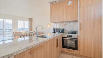 Eine moderne Küche mit Holdekor, einer Marmorarbeitsplatte, einem eingebauten Backofen und einem großen Fenster mit Blick auf die Stadt.