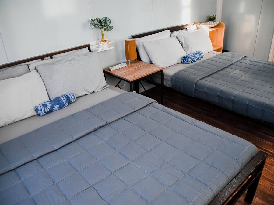 Two beds with grey bedding, wooden headboards, and bedside tables with lamps.