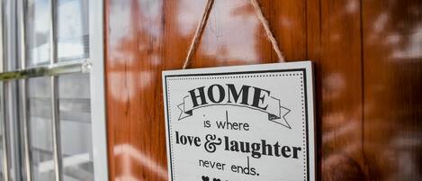 Un letrero con el texto: 'HOGAR es donde el amor y la risa nunca terminan'.