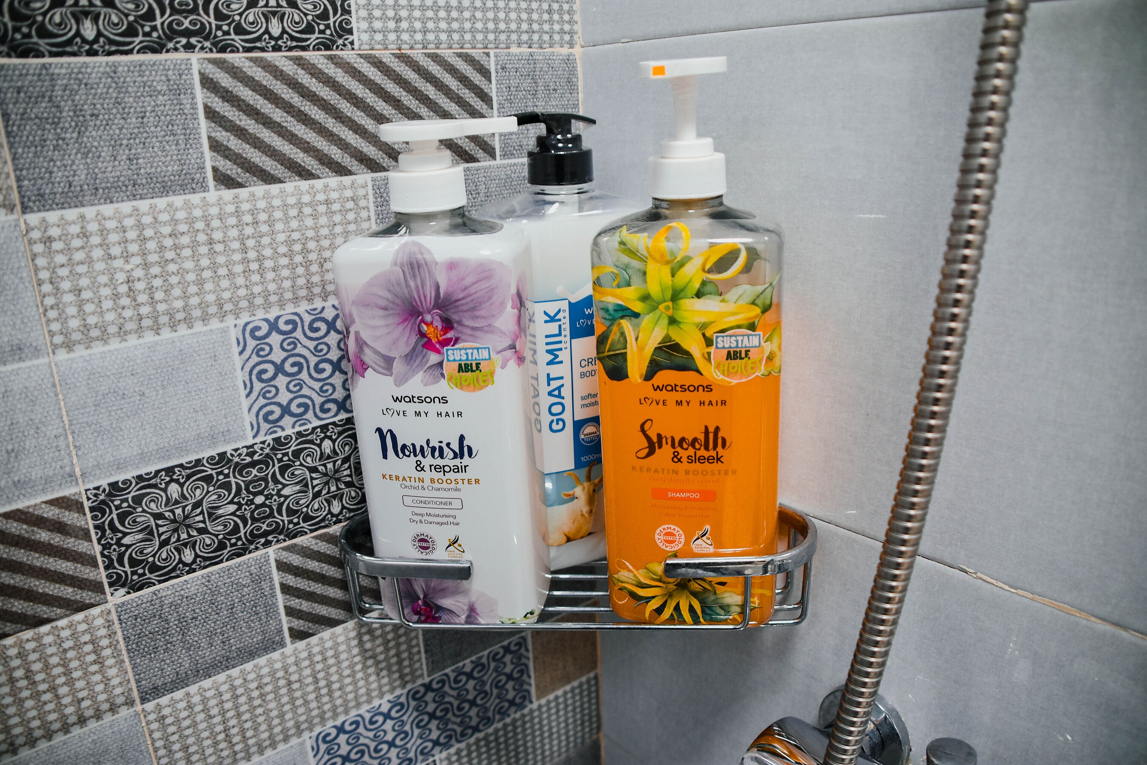 Des produits de toilette sont posés sur une étagère de la salle de bain, notamment un flacon de la gamme Nourish & Repair, un flacon de la gamme Go Milk et un flacon de la gamme Smooth & Sleek.
