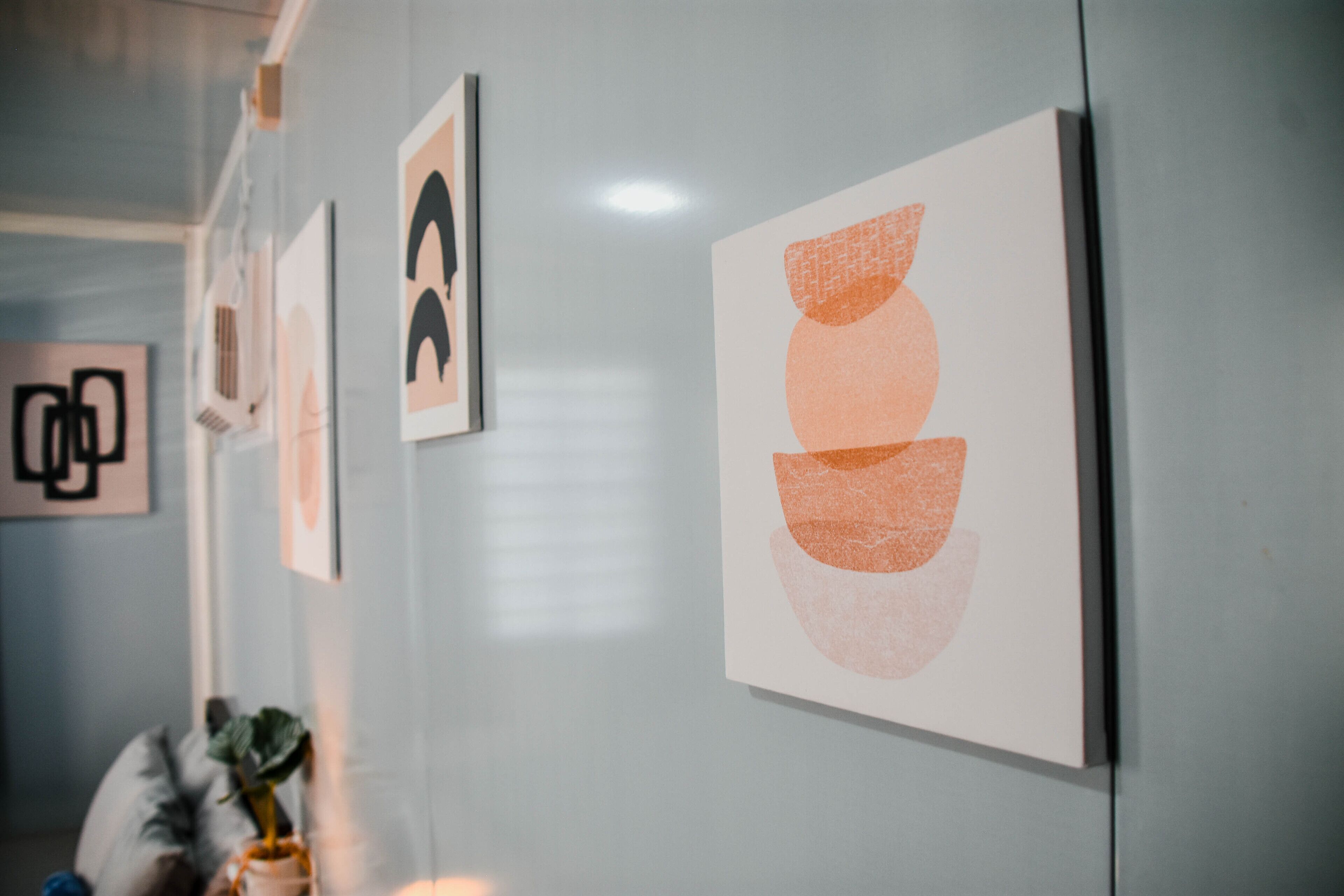 A wall with several framed artworks, including abstract designs and a portrait.