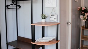 Una estantería de madera con varios niveles, una planta en maceta y un cartel enmarcado en la pared.