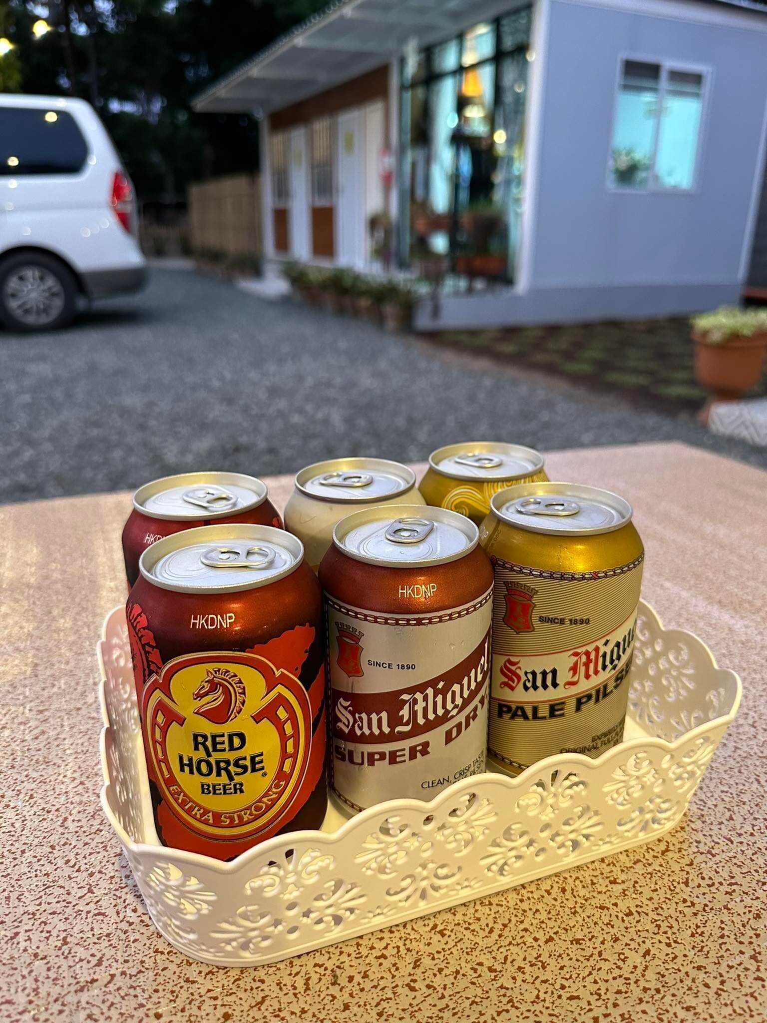 A tray with six beer cans on a textured surface.