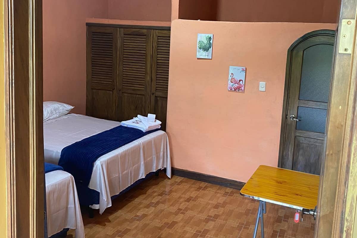 Une pièce comprenant un lit, une petite table, une armoire et une porte.