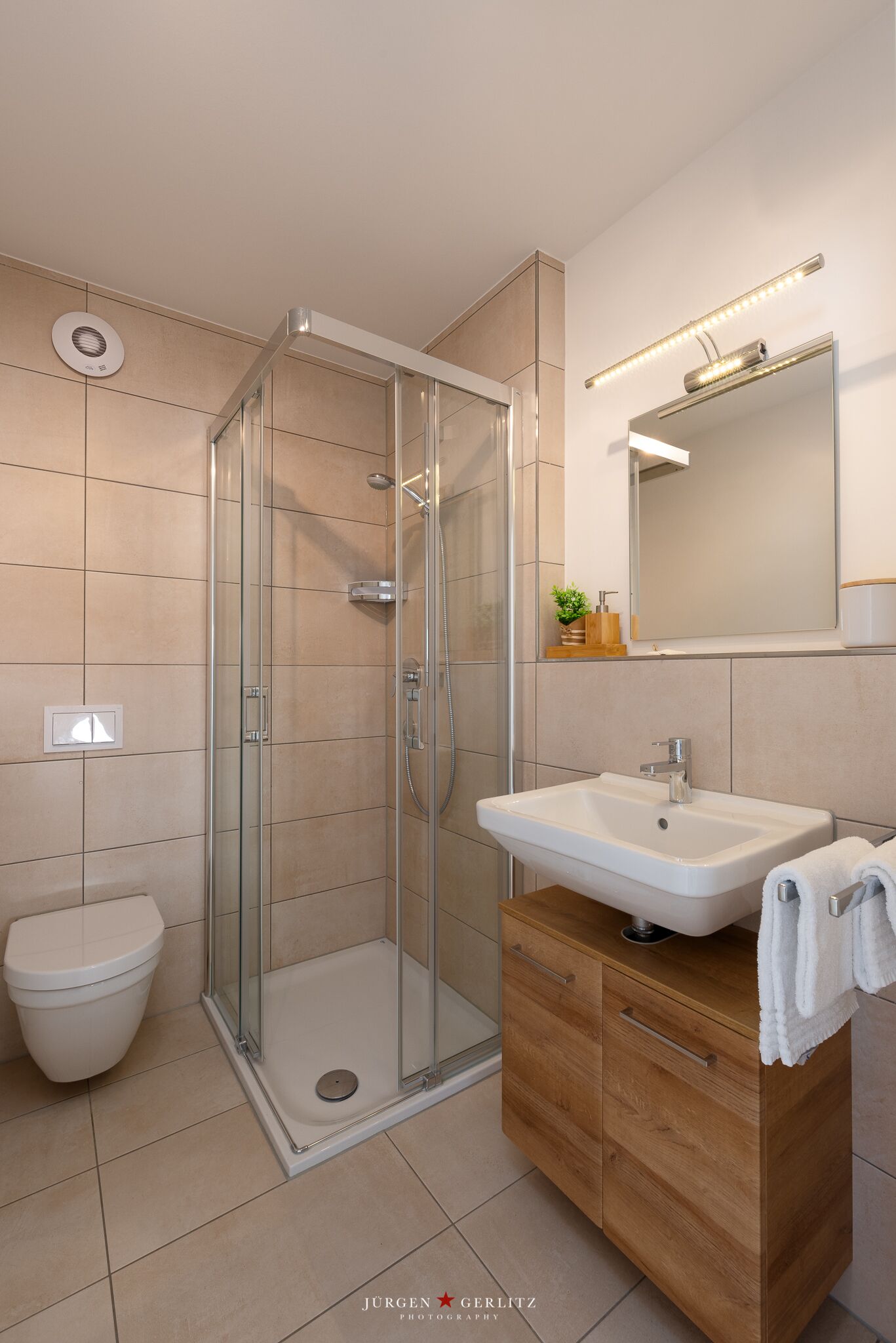 Une salle de bain moderne avec une douche à parois de verre, un lavabo blanc et un meuble-lavabo en bois.