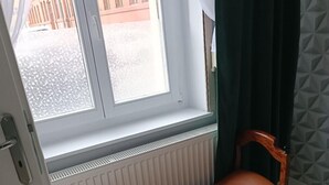 A room with a bench by a window, a radiator below, and a patterned wall. - Apartament Fantazja 1 (Torun)