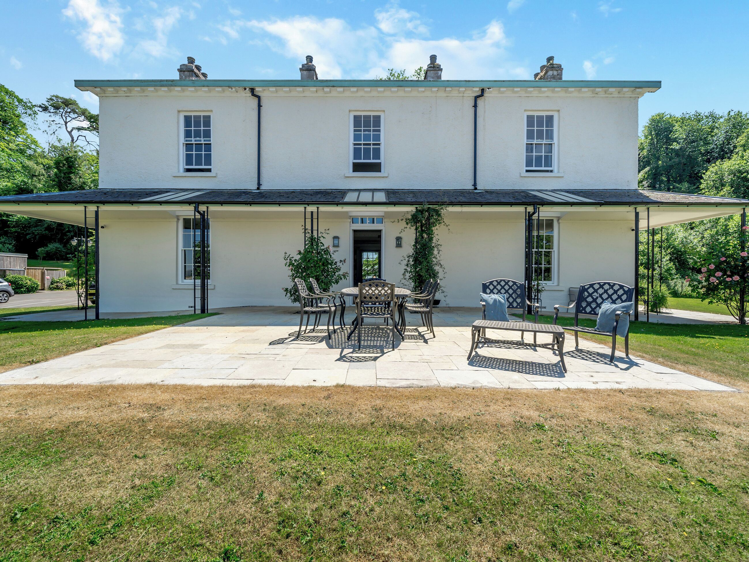 Une maison à deux étages dotée d’un patio couvert aménagé avec du mobilier d’extérieur.