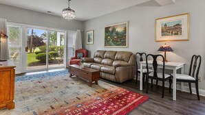 A spacious living room with a leather sofa, dining table, and chairs, a chandelier, and two framed paintings on the wall. - World Tour Golf Course overlooking the greens. Spacious 2 Bed 2 Bath on the 9th. (Myrtle Beach)