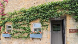 A stone building with a wooden door and two windows. - Yarn Cottage (Broadway)