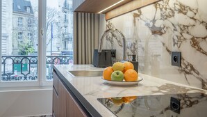 Una cocina moderna con salpicadero de mármol, un lavamanos de acero inoxidable y un cuenco de frutas en la encimera.