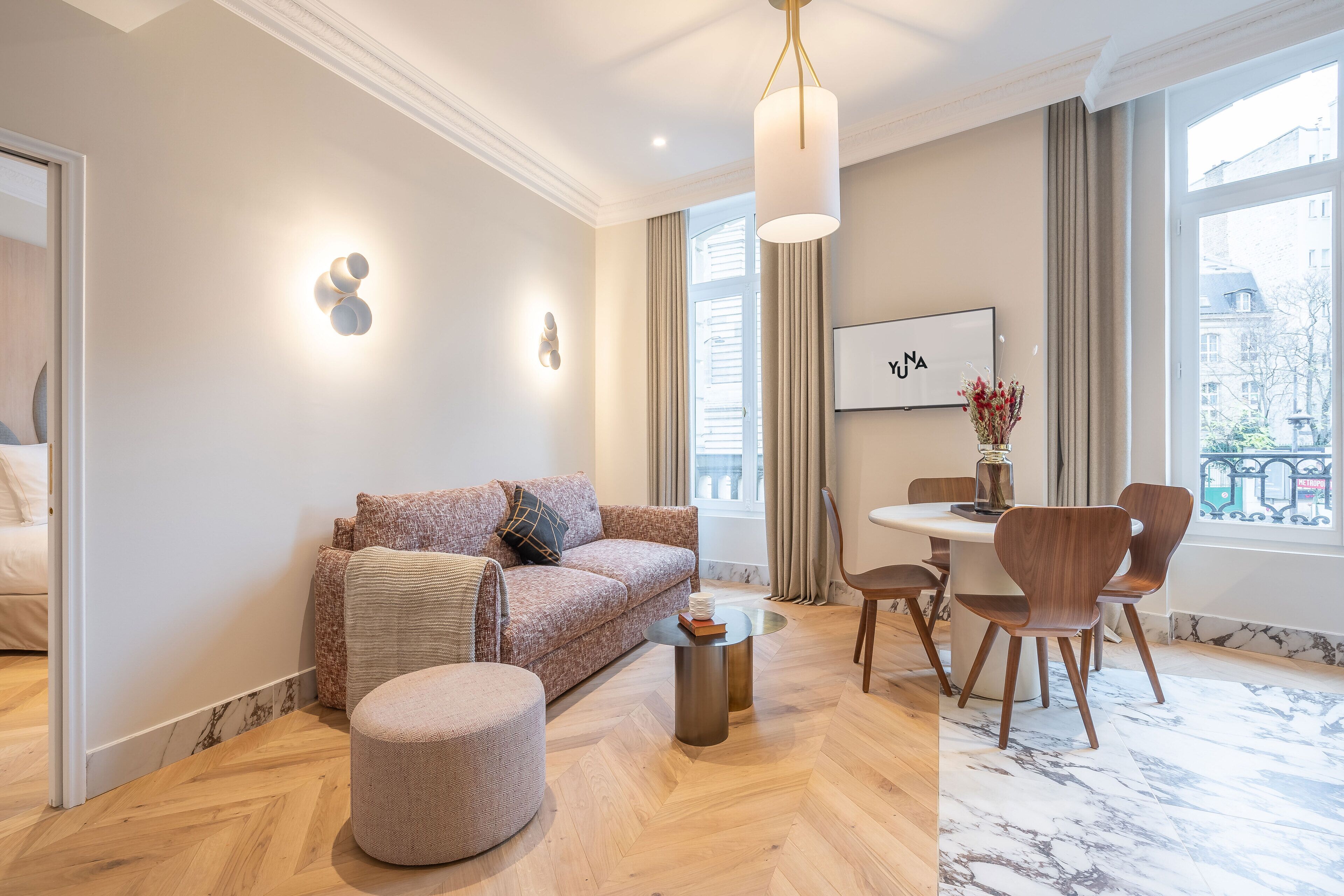 A modern living room with a sofa, ottoman, and dining table with chairs.