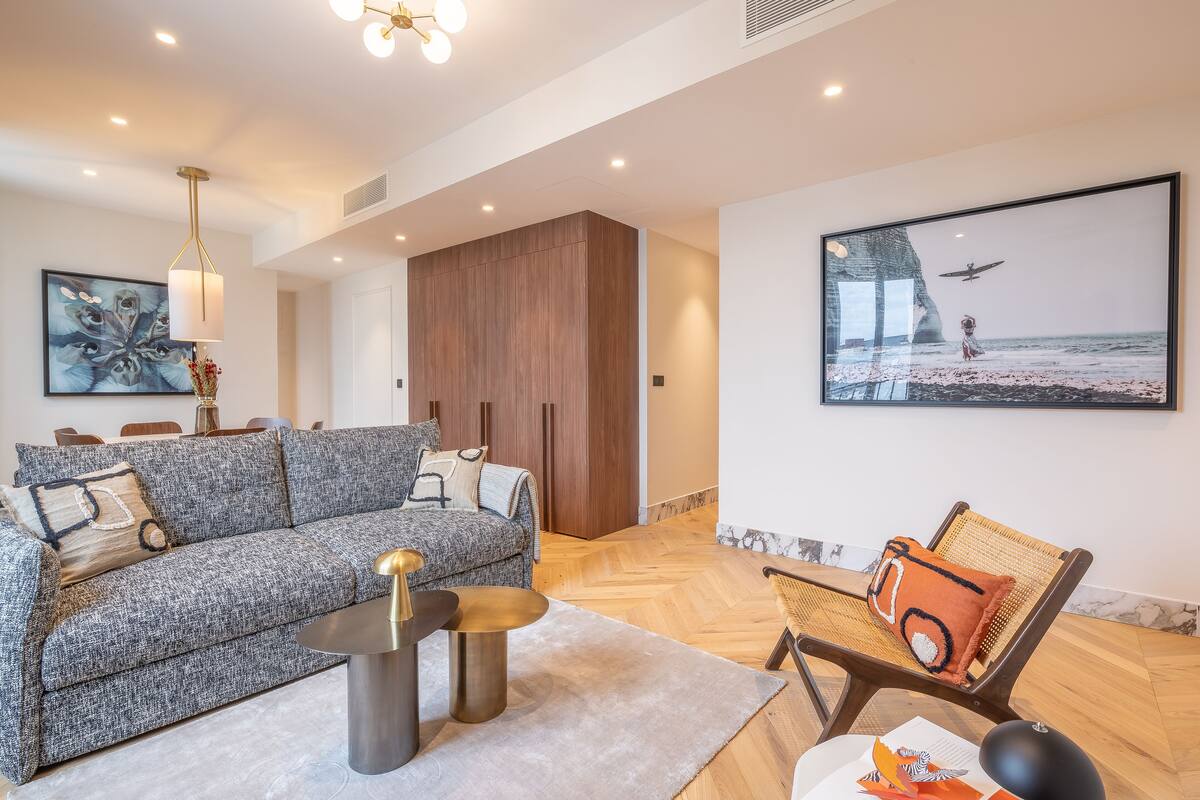 Ein modernes Wohnzimmer mit einem grauen Sofa, einem runden Couchtisch und Holzboden.
