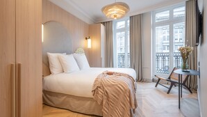 Habitación de hotel con una cama grande, una mesita y una silla.