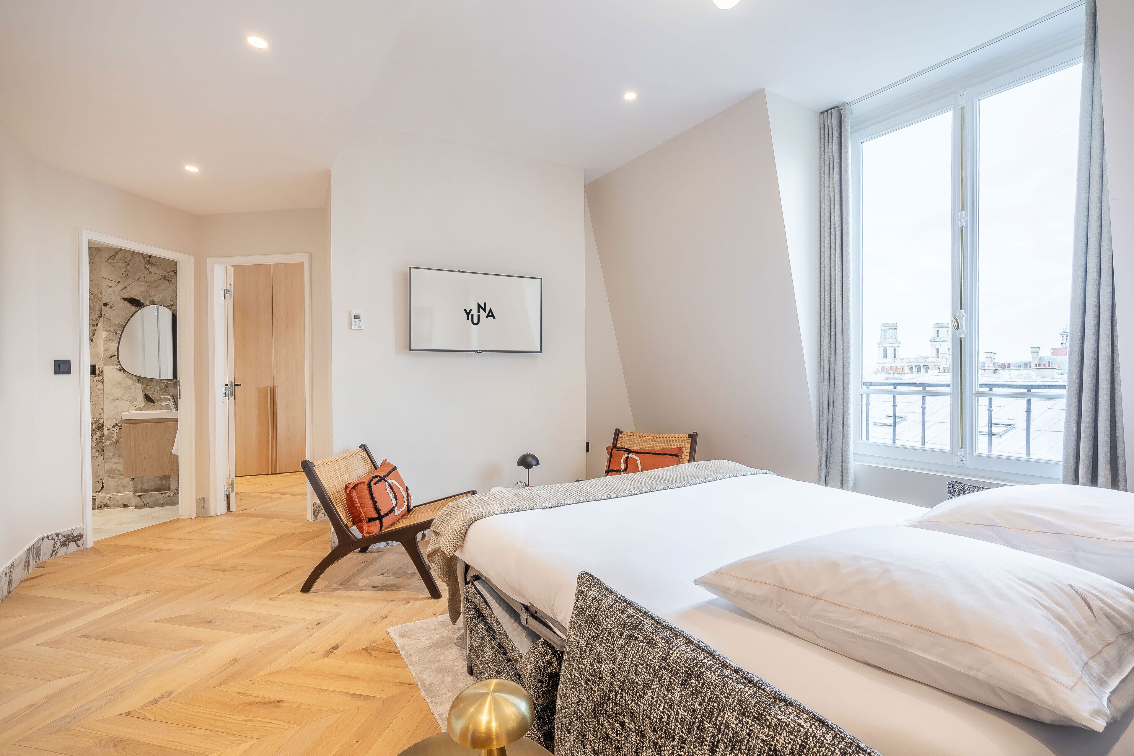 Un dormitorio moderno con una cama grande, vistas de la ciudad y un baño con pared de piedra.