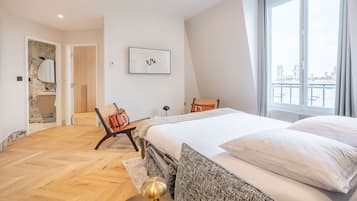 Un dormitorio moderno con una cama grande, vistas de la ciudad y un baño con pared de piedra.