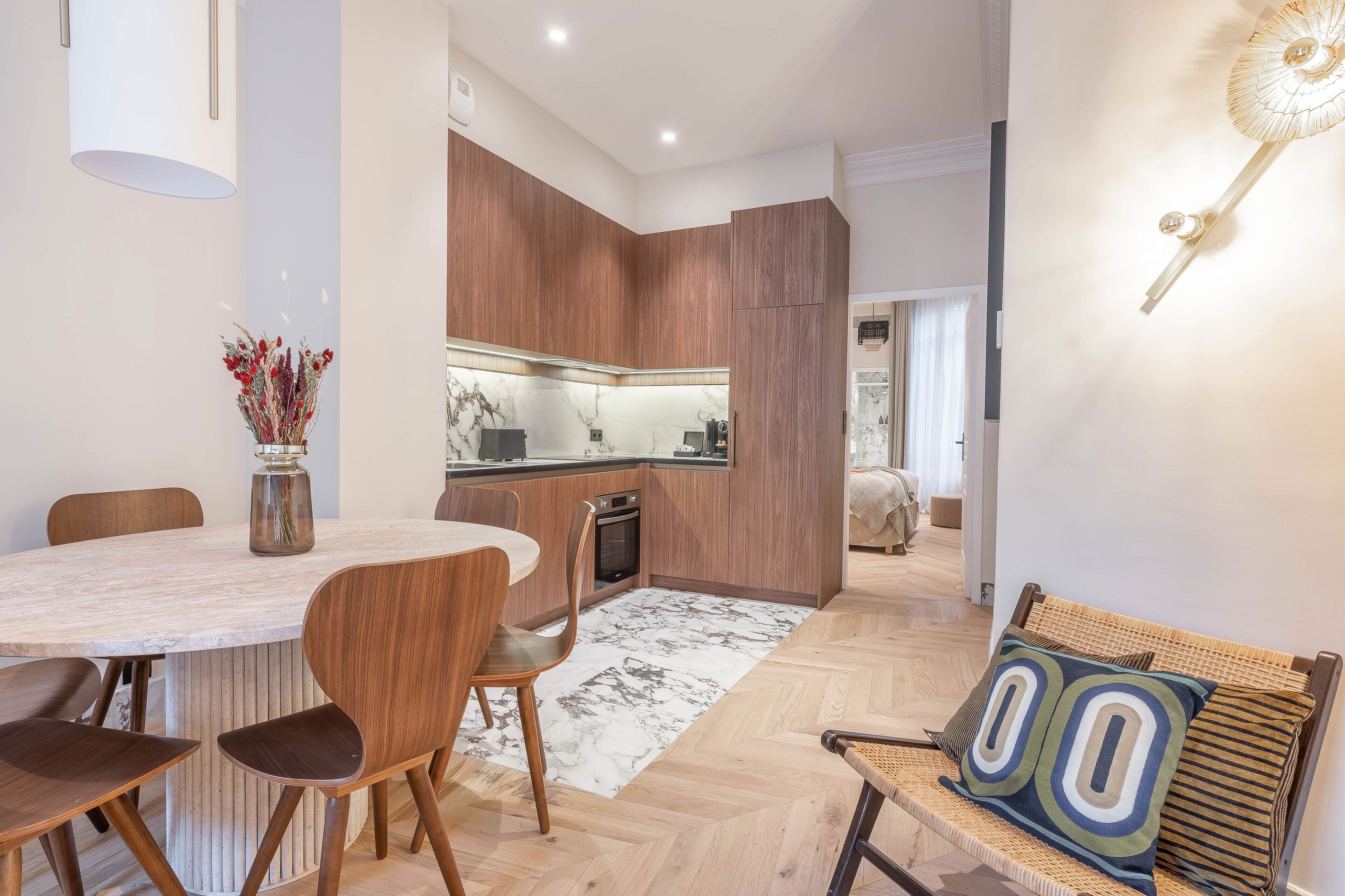 Une cuisine moderne avec des meubles en bois, un pare-feu en marbre et un coin repas comprenant une table en marbre et des chaises en bois.