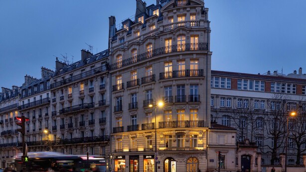 Un edificio de varios pisos con detalles arquitectónicos ornamentados, incluyendo balcones y ventanas amplias.