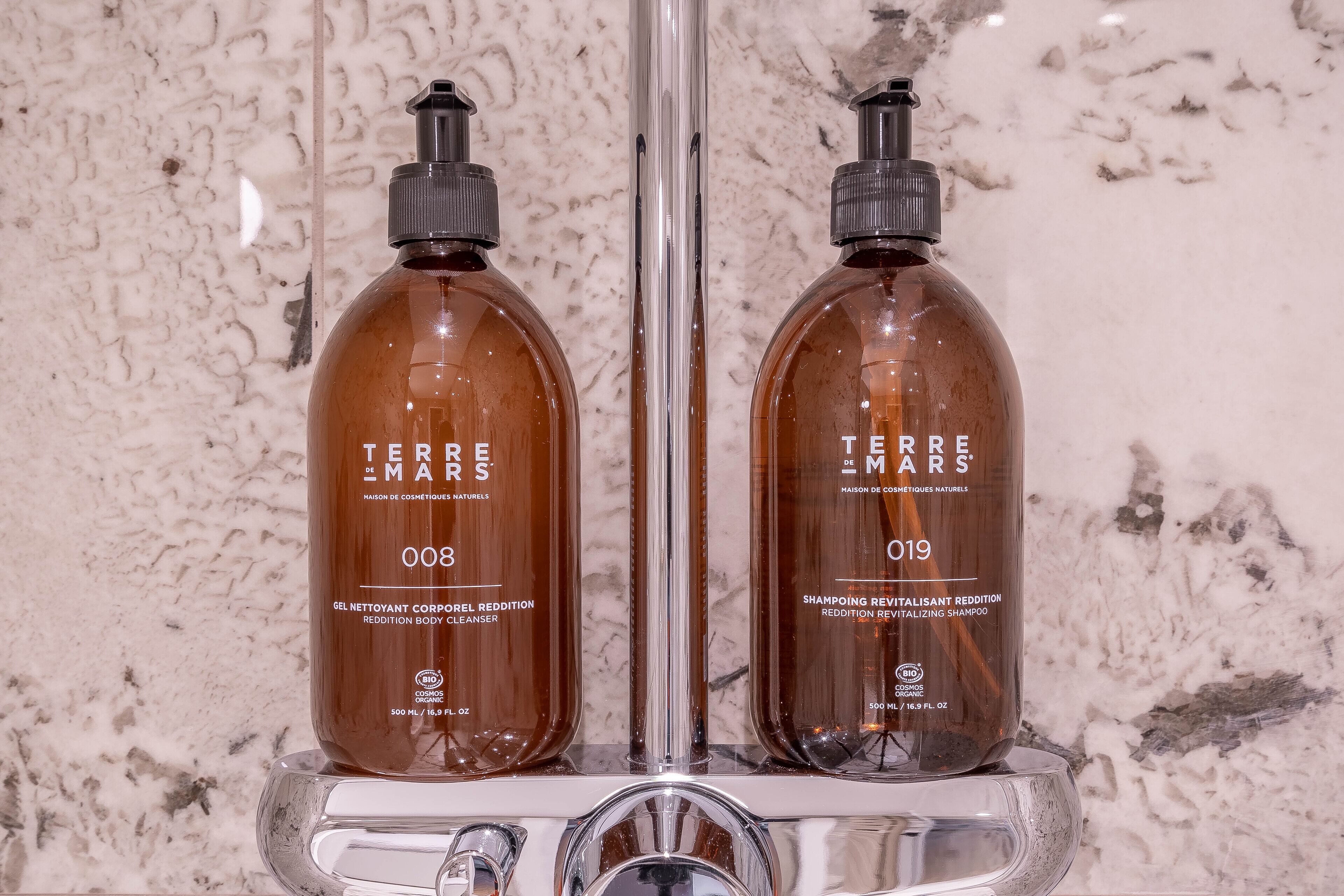 Dos botellas de limpiador corporal y champú revitalizante Terre de Mars sobre una encimera de baño.