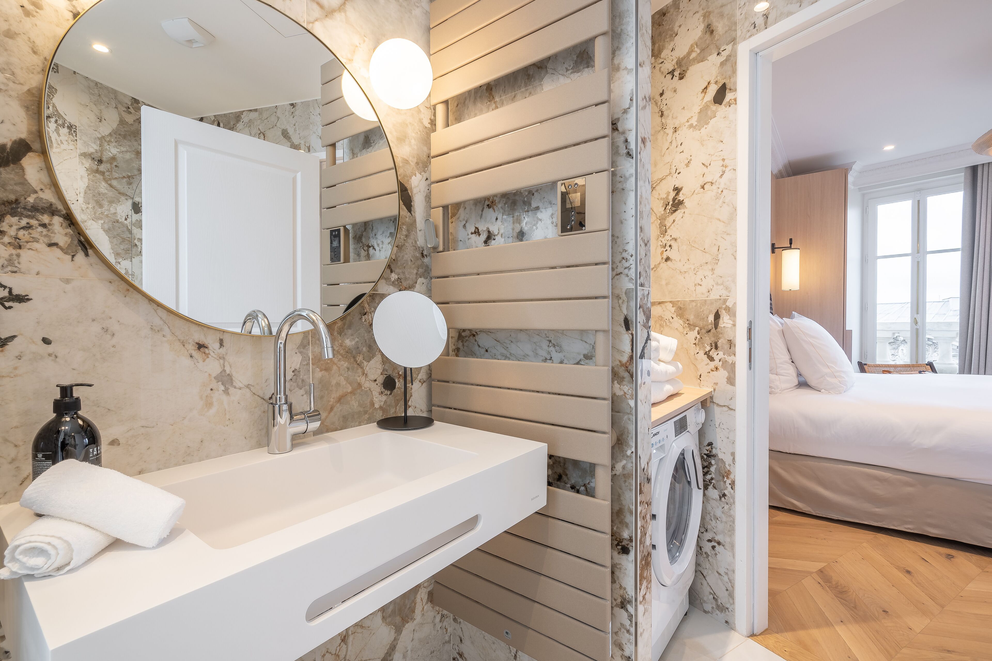Een moderne badkamer met een wit wastafelmeubel, een ronde spiegel en een ingebouwde wasmachine.
