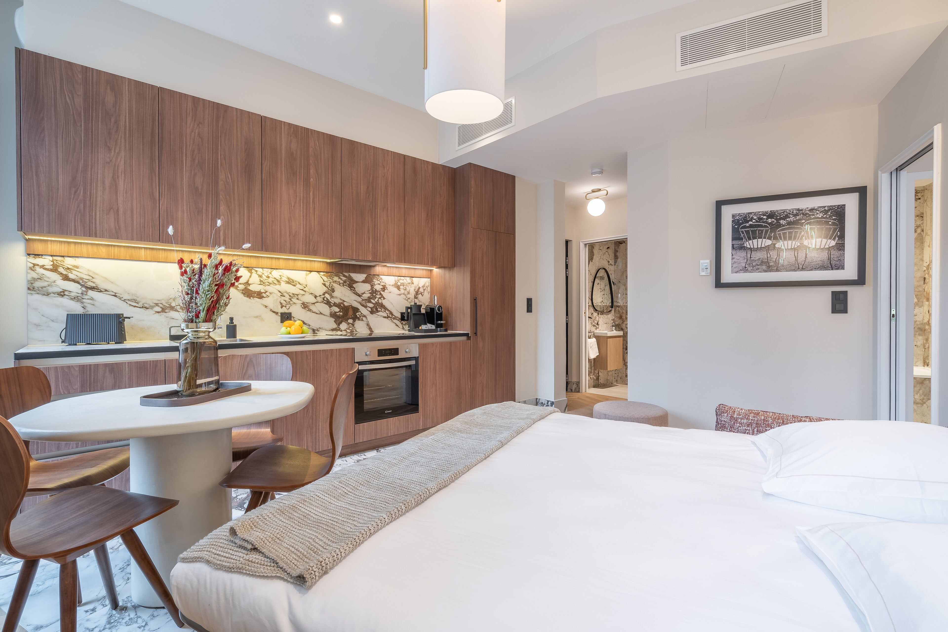 Una habitación de hotel moderna con cocina de mármol, zona de comedor y una cama grande.