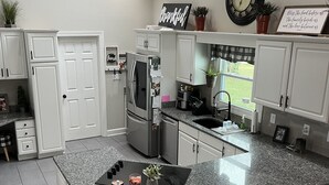 Eine moderne Küche mit weißen Schränken, einer Granitarbeitsplatte und einer integrierten Kücheninsel mit Barhocker.