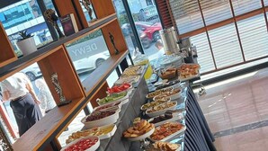 A buffet with various food items and a view of the street outside. - Abbara Hotel  (Izmir)