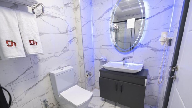 A bathroom with a toilet, sink, and mirror. - Abbara Hotel  (Izmir)