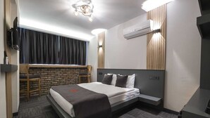 Una habitación de hotel moderna con cama, escritorio y ventana con cortinas.