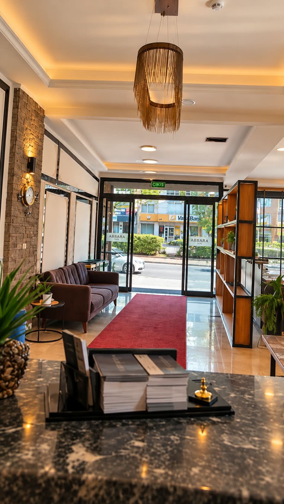 Vestíbulo de hotel con mostrador de recepción, zona de estar y vistas a la calle.
