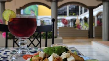 Une table avec une assiette de nourriture et une boisson, placée dans une pièce donnant sur un balcon et un espace extérieur.