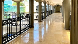 Un couloir doté d’un sol carrelé, de colonnes et d’une rambarde.