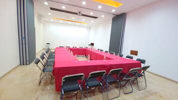 Un salón de conferencias con una larga mesa, sillas y una pantalla para proyector.