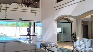 Un hall d’entrée spacieux, agrémenté d’un lustre, d’un coin salon et offrant une vue sur l’extérieur.