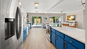 Une cuisine moderne avec des armoires bleues, des appareils en acier inoxydable et un grand îlot central.