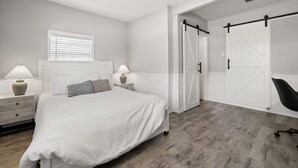 Une chambre à coucher avec un lit, des tables de chevet, une fenêtre et une porte coulissante.