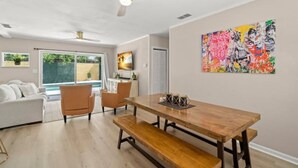 Un salon moderne avec une table à manger en bois, deux chaises, un canapé et un ventilateur de plafond.